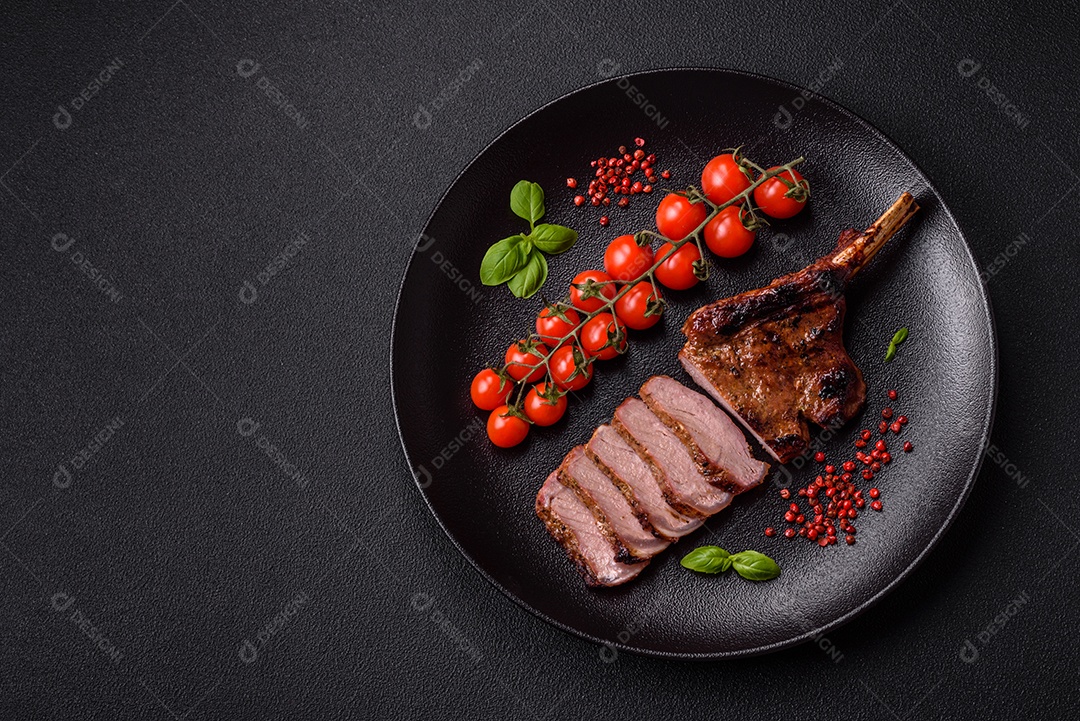 Delicioso bife de porco suculento com sal, especiarias e ervas sobre um fundo escuro de concreto