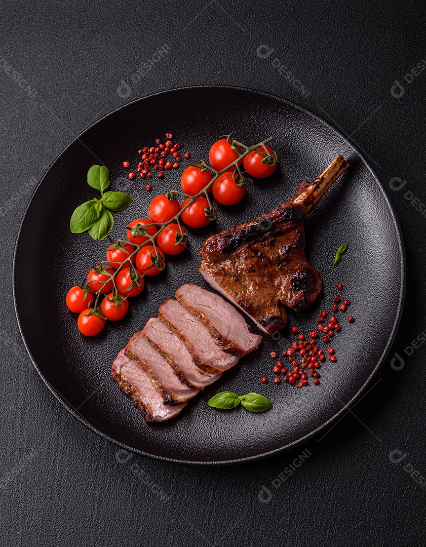 Delicioso bife de porco suculento com sal, especiarias e ervas sobre um fundo escuro de concreto