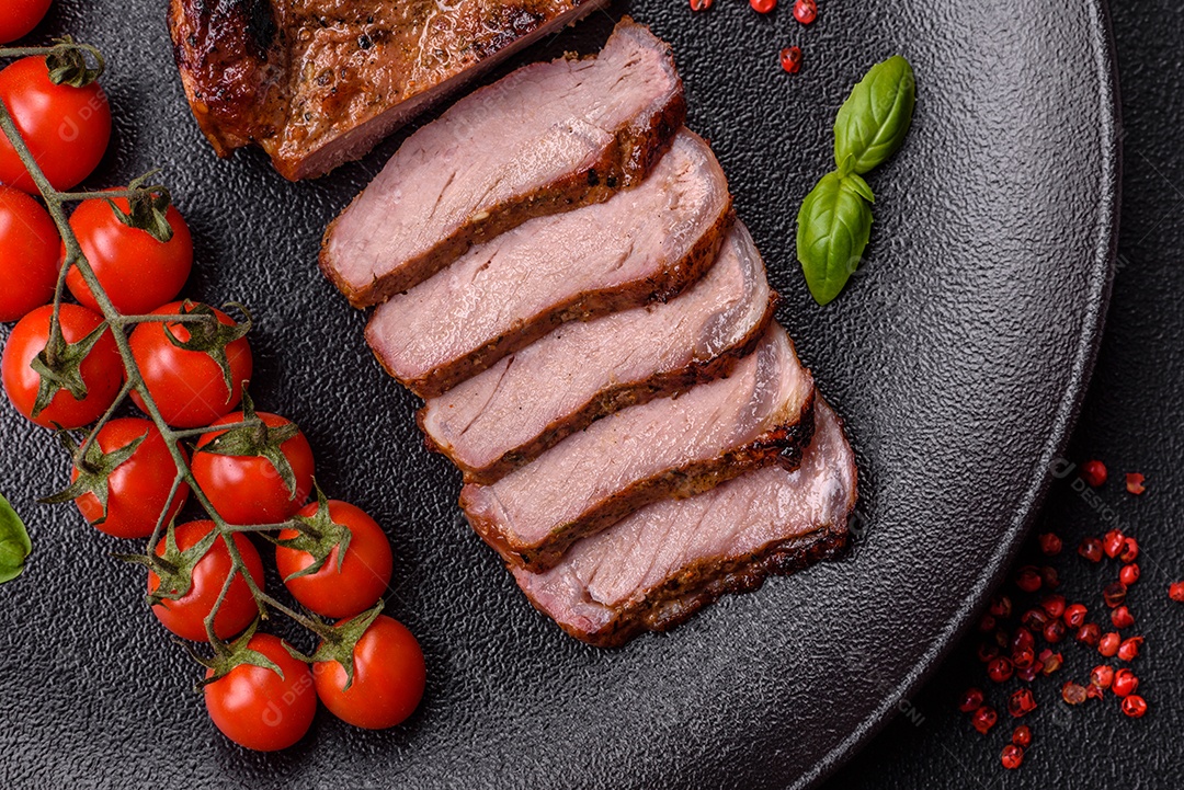 Delicioso bife de porco suculento com sal, especiarias e ervas sobre um fundo escuro de concreto