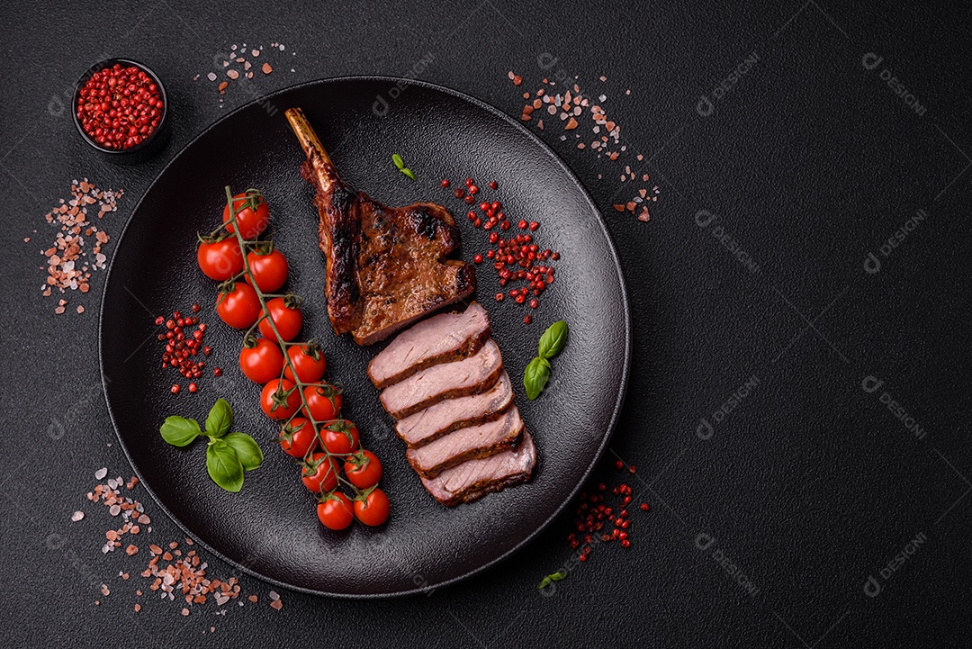 Delicioso bife de porco suculento com sal, especiarias e ervas sobre um fundo escuro de concreto