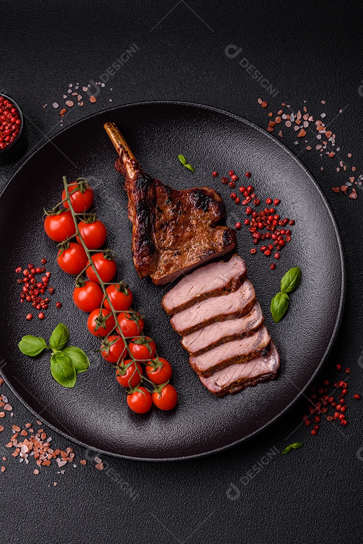 Deliciosas asas de frango suculentas assadas na grelha com sal, especiarias e ervas sobre um fundo escuro de concreto