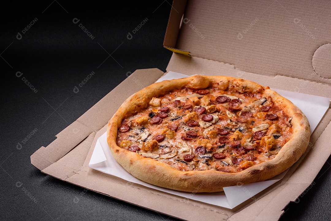 Deliciosa pizza com salsicha, queijo, tomate, sal, especiarias e ervas sobre um fundo escuro de concreto