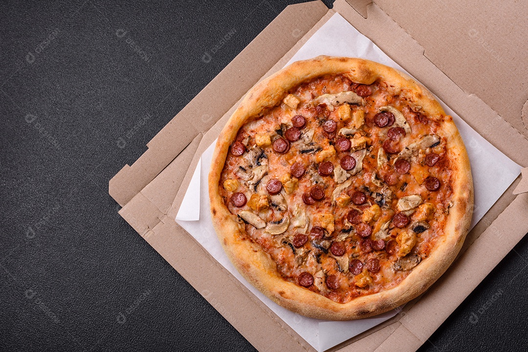 Deliciosa pizza com salsicha, queijo, tomate, sal, especiarias e ervas sobre um fundo escuro de concreto