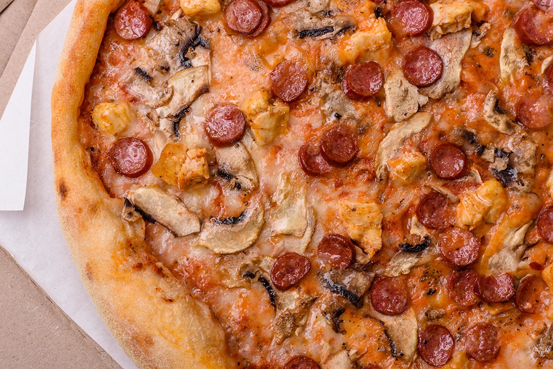 Deliciosa pizza com salsicha, queijo, tomate, sal, especiarias e ervas sobre um fundo escuro de concreto