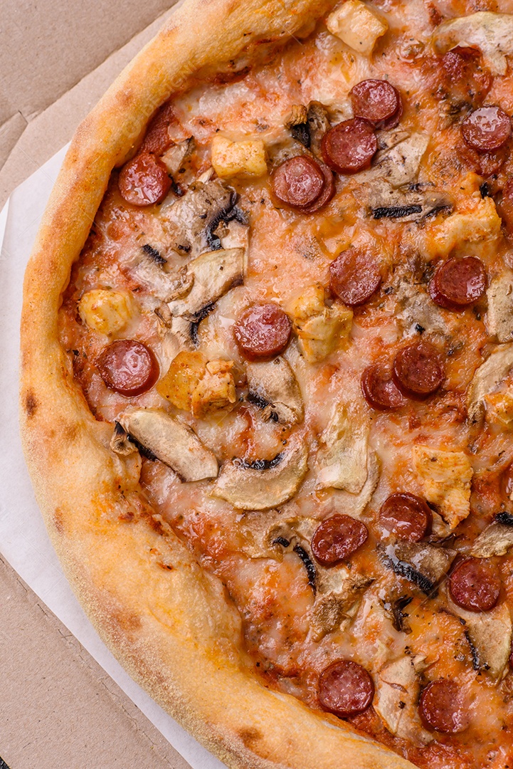 Deliciosa pizza com salsicha, queijo, tomate, sal, especiarias e ervas sobre um fundo escuro de concreto