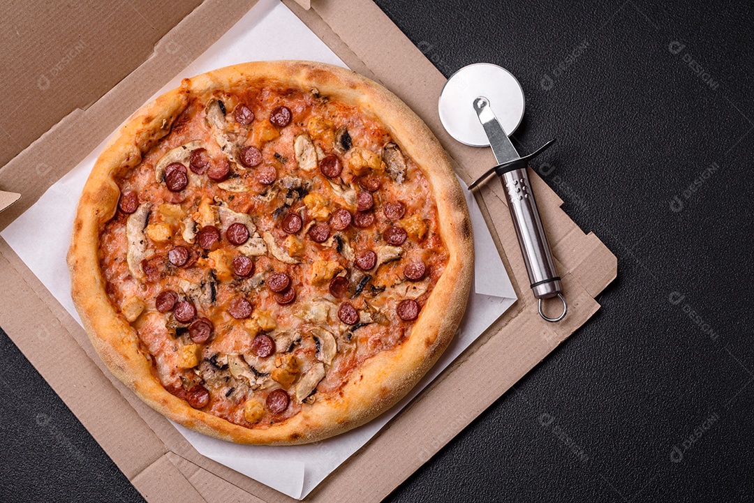 Deliciosa pizza com salsicha, queijo, tomate, sal, especiarias e ervas sobre um fundo escuro de concret