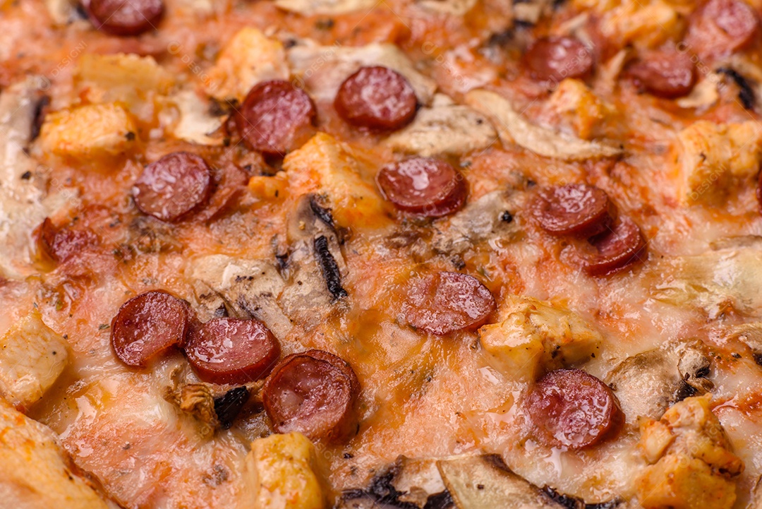 Deliciosa pizza com salsicha, queijo, tomate, sal, especiarias e ervas sobre um fundo escuro de concreto