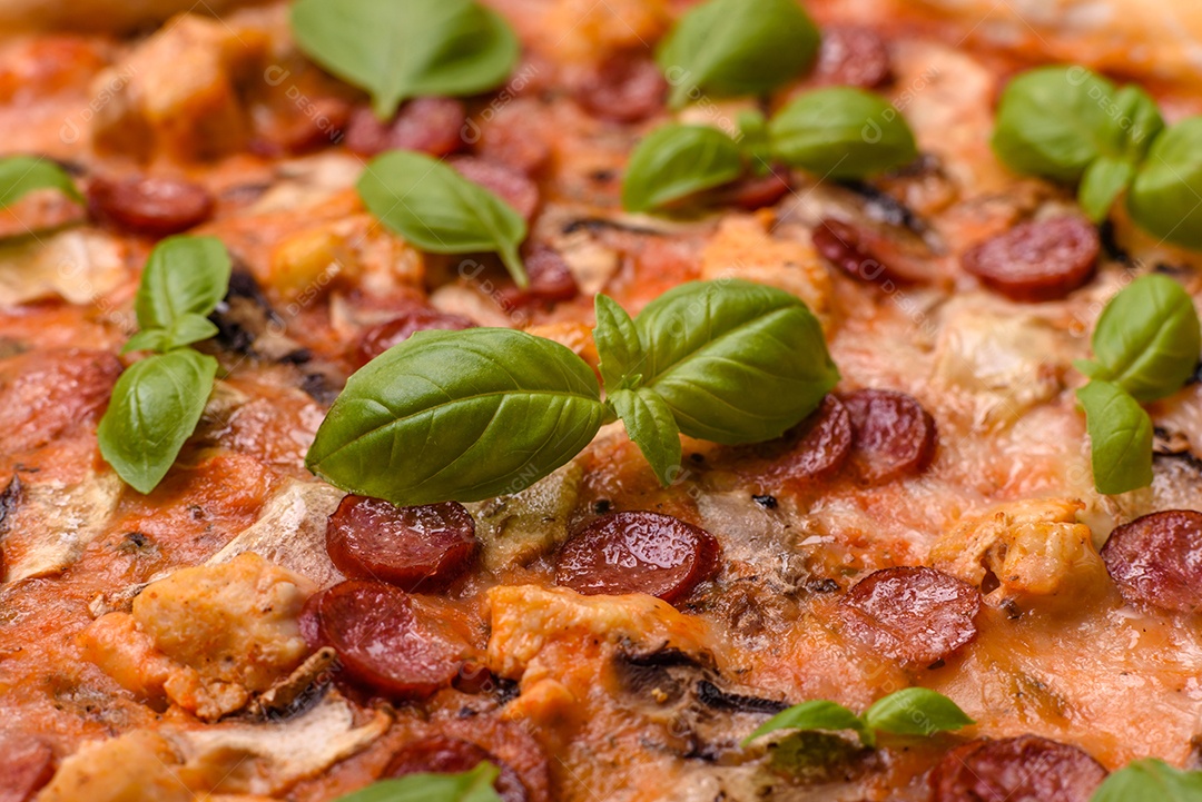 Deliciosa pizza com salsicha, queijo, tomate, sal, especiarias e ervas sobre um fundo escuro de concreto