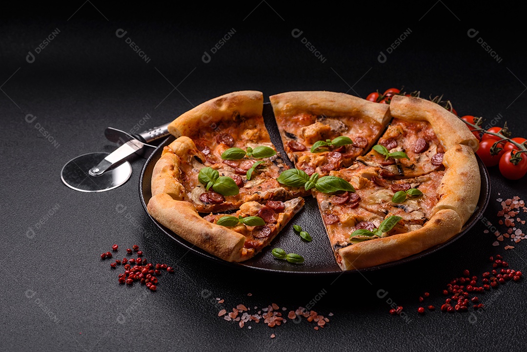 Deliciosa pizza com salsicha, queijo, tomate, sal, especiarias e ervas sobre um fundo escuro de concreto