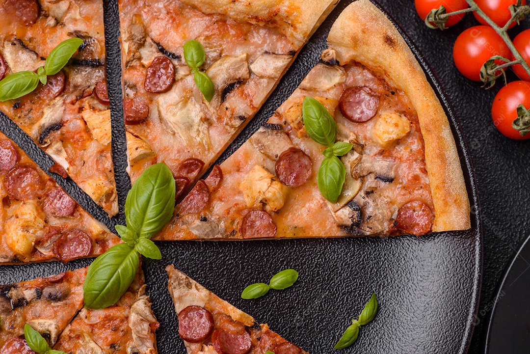 Deliciosa pizza com salsicha, queijo, tomate, sal, especiarias e ervas sobre um fundo escuro de concreto