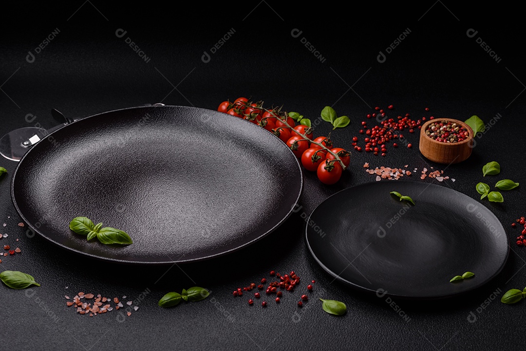 Ingredientes sal, especiarias, ervas e tomates sobre um fundo escuro de concreto. Cozinhando em casa