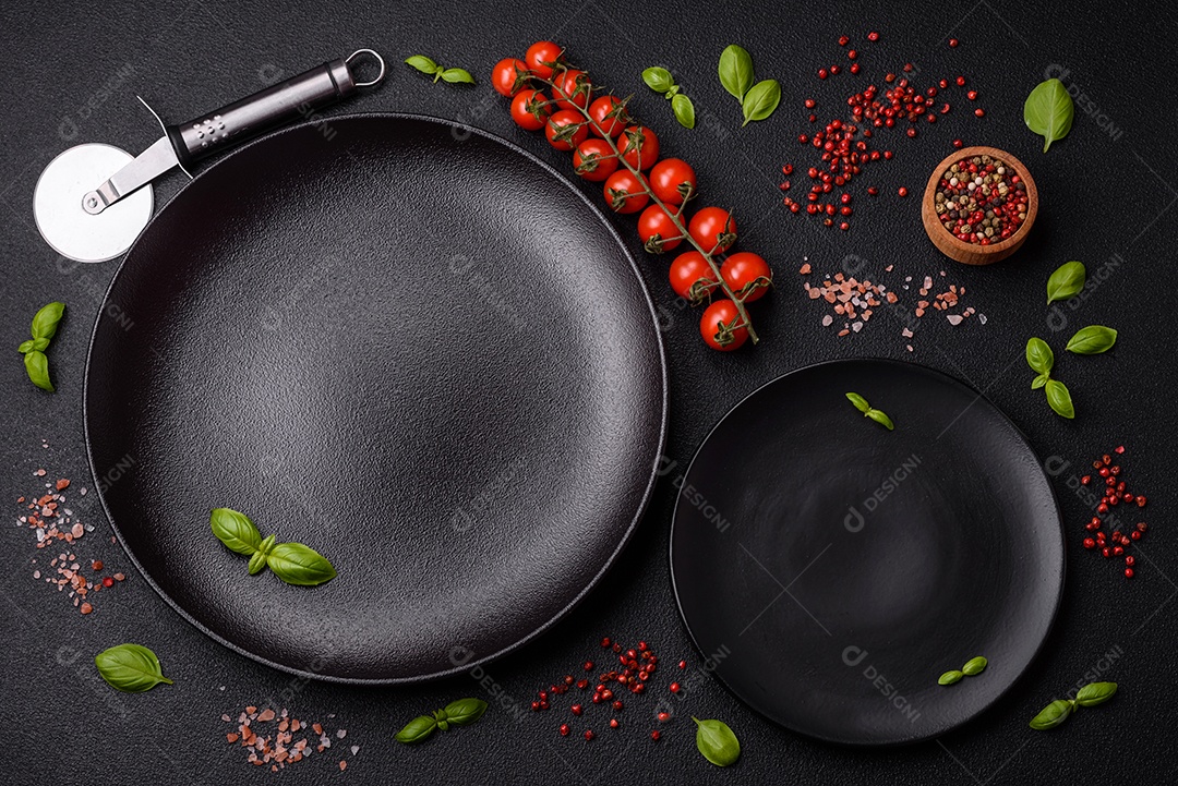 Ingredientes sal, especiarias, ervas e tomates sobre um fundo escuro de concreto. Cozinhando em casa