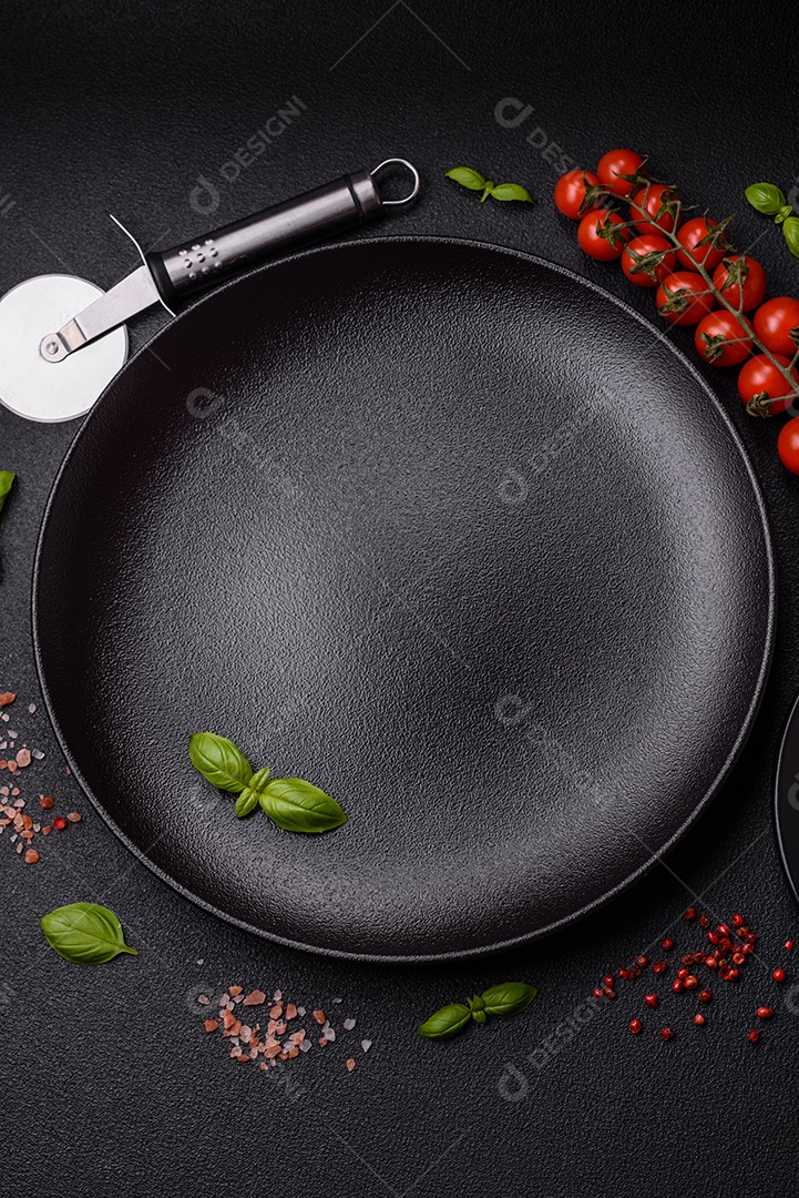 Ingredientes sal, especiarias, ervas e tomates sobre um fundo escuro de concreto. Cozinhando em casa