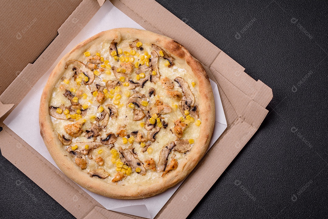 Deliciosa pizza com milho, queijo, tomate e cogumelos, sal, especiarias e ervas sobre fundo escuro de concreto