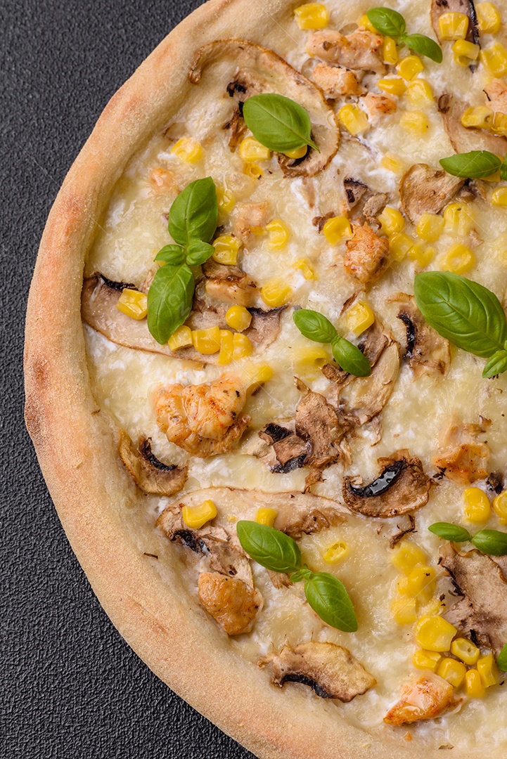 Deliciosa pizza com milho, queijo, tomate e cogumelos, sal, especiarias e ervas sobre fundo escuro de concreto