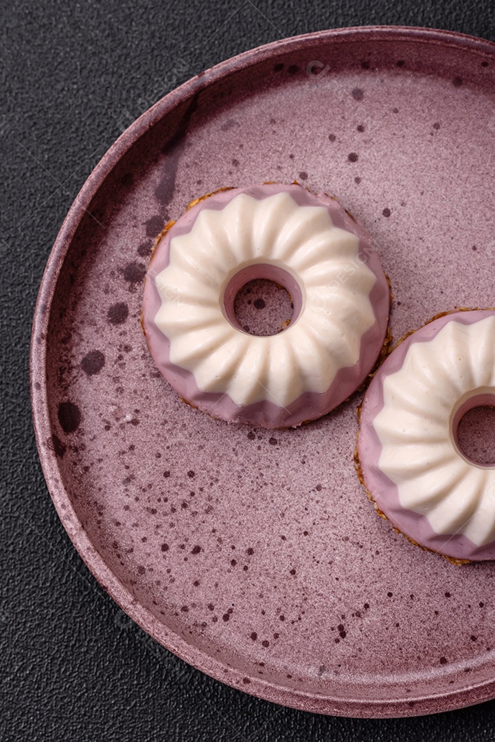 Delicioso cheesecake redondo rosa e branco, sem lactose, sem açúcar, nutrição saudável, sobre um fundo escuro de concreto