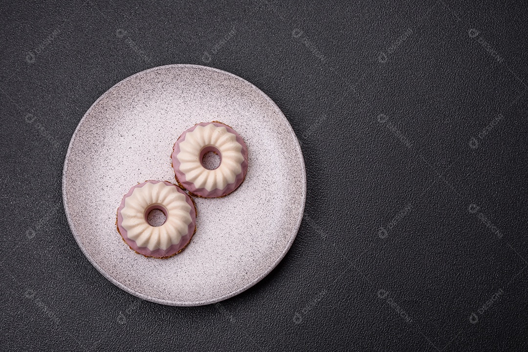 Delicioso cheesecake redondo rosa e branco, sem lactose, sem açúcar, nutrição saudável, sobre um fundo escuro de concreto