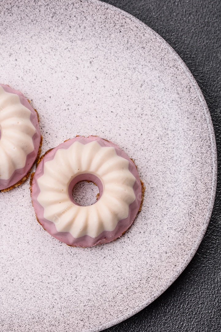 Delicioso cheesecake redondo rosa e branco, sem lactose, sem açúcar, nutrição saudável, sobre um fundo escuro de concreto