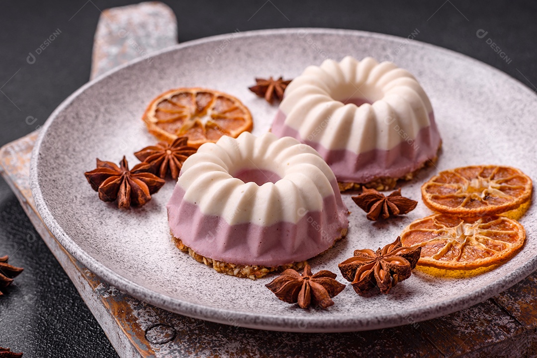 Delicioso cheesecake redondo rosa e branco, sem lactose, sem açúcar, nutrição saudável, sobre um fundo escuro de concreto