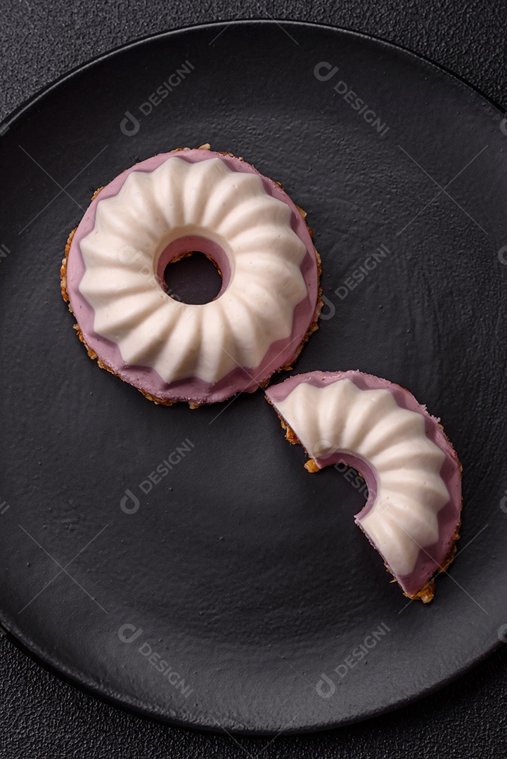 Delicioso cheesecake redondo rosa e branco, sem lactose, sem açúcar, nutrição saudável, sobre um fundo escuro de concreto