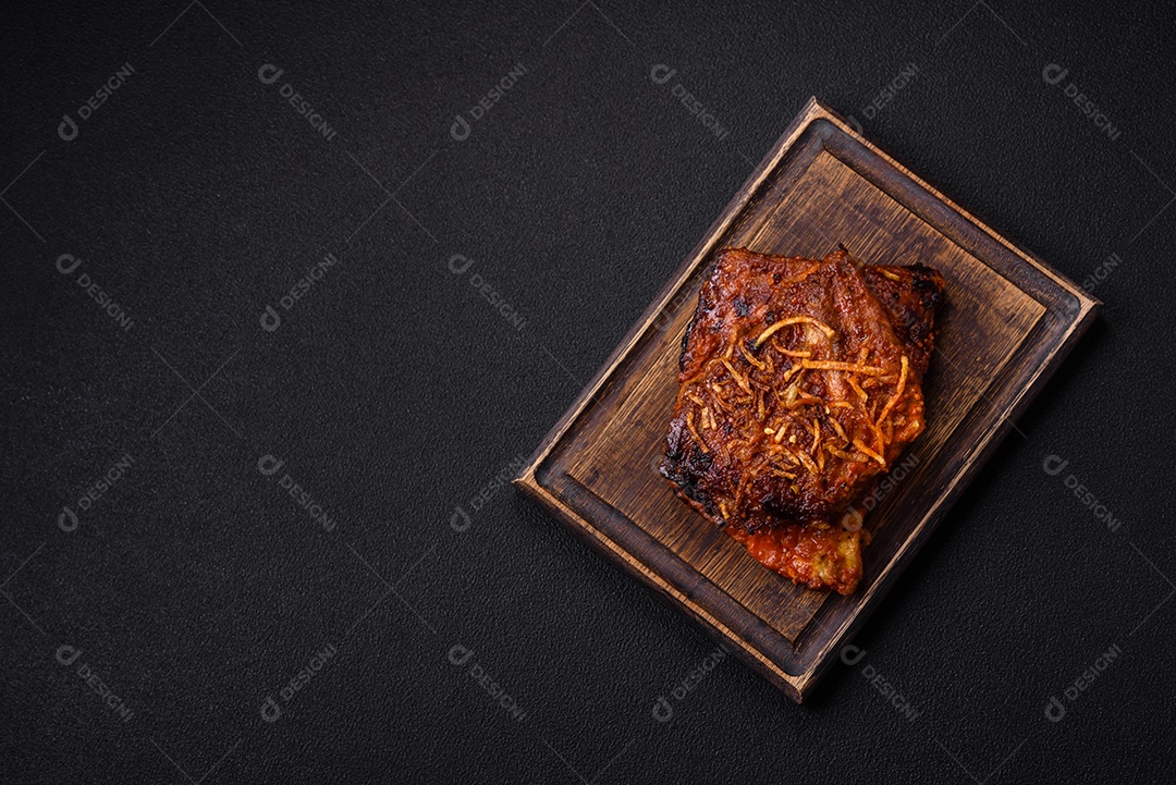 Deliciosas costelas de porco ou de vaca assadas na grelha com sal, especiarias e ervas sobre um fundo escuro de concreto