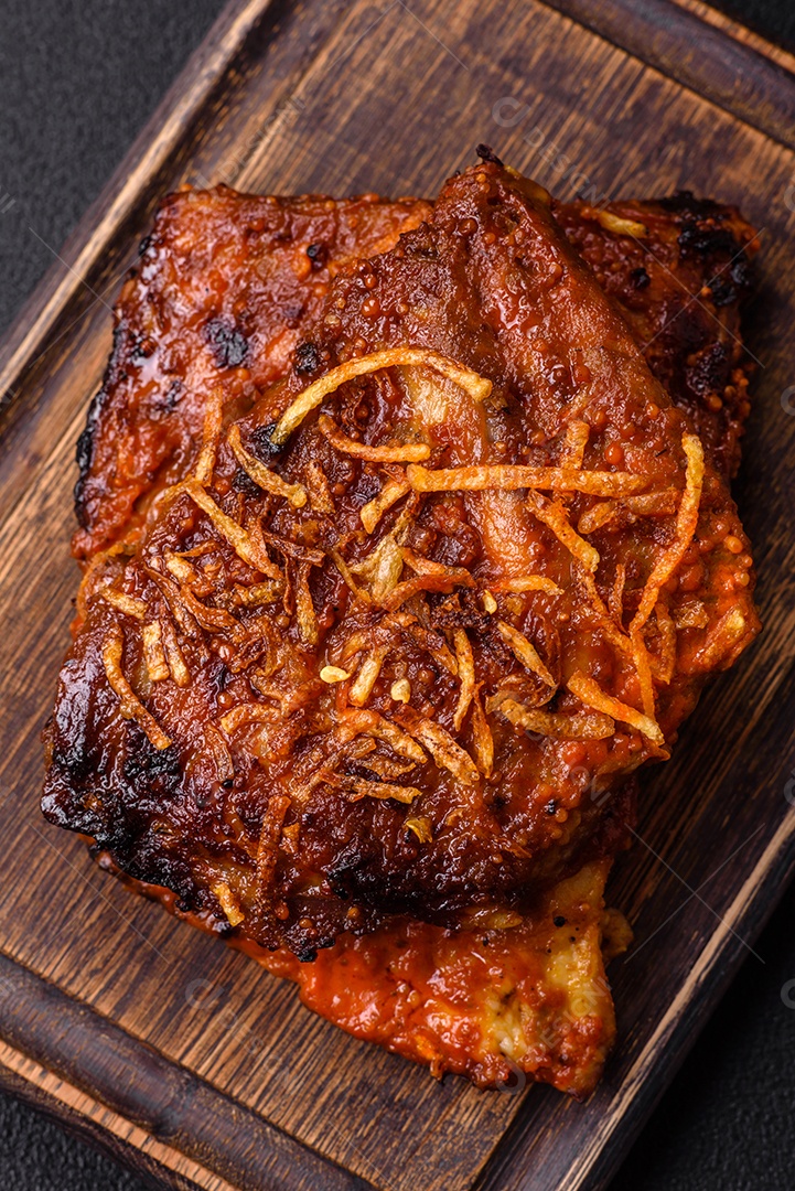 Deliciosas costelas de porco ou de vaca assadas na grelha com sal, especiarias e ervas sobre um fundo escuro de concreto