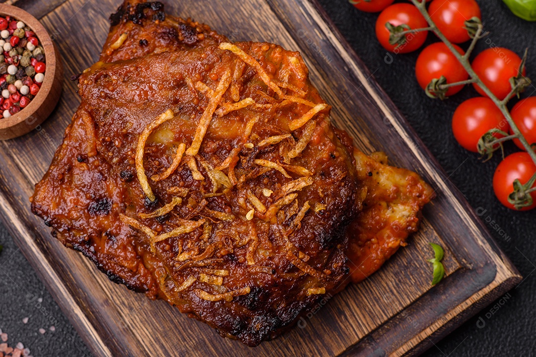 Deliciosas costelas de porco ou de vaca assadas na grelha com sal, especiarias e ervas sobre um fundo escuro de concreto