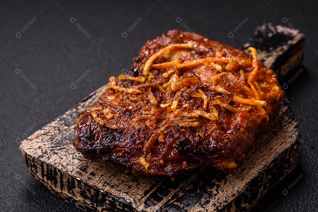 Deliciosas costelas de porco ou de vaca assadas na grelha com sal, especiarias e ervas sobre um fundo escuro de concreto