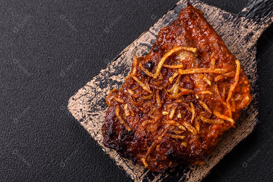 Deliciosas costelas de porco ou de vaca assadas na grelha com sal, especiarias e ervas sobre um fundo escuro de concreto