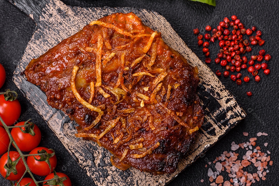 Deliciosas costelas de porco ou de vaca assadas na grelha com sal, especiarias e ervas sobre um fundo escuro de concreto