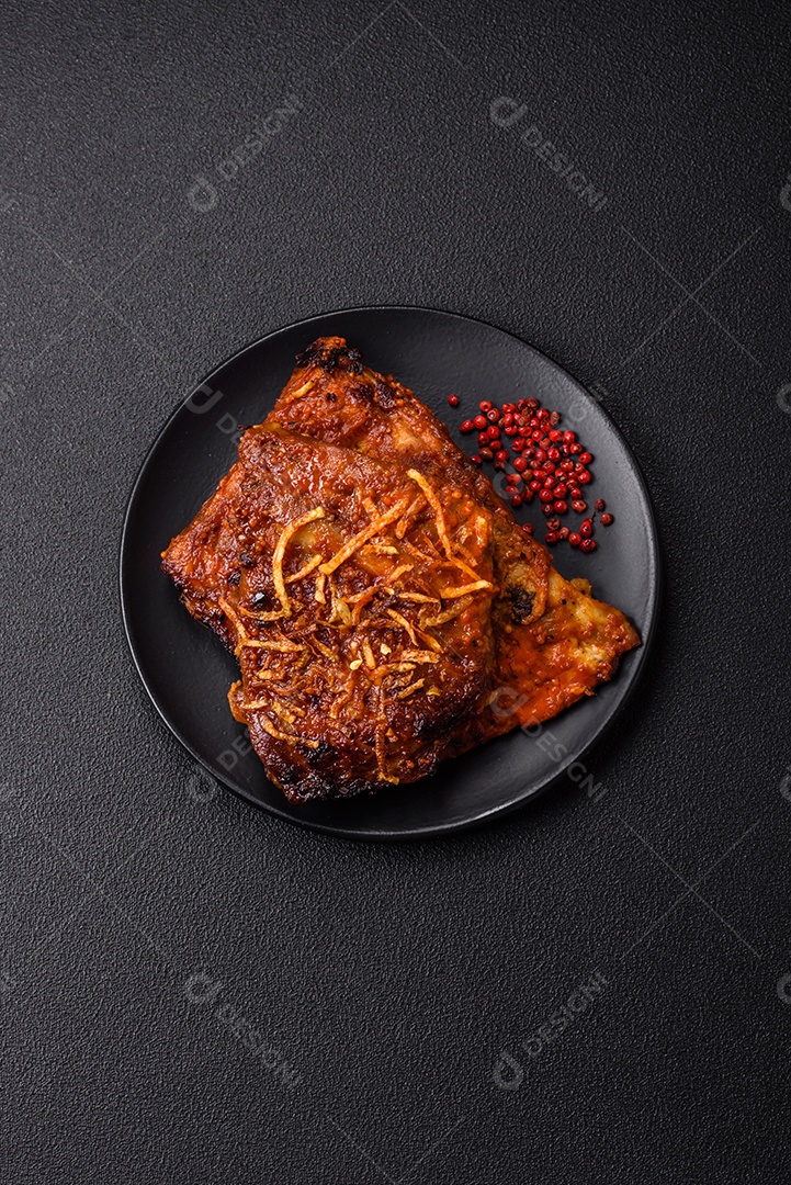 Deliciosas costelas de porco ou de vaca assadas na grelha com sal, especiarias e ervas sobre um fundo escuro de concreto