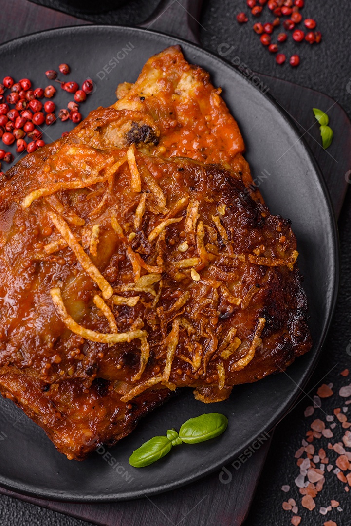 Deliciosas costelas de porco ou de vaca assadas na grelha com sal, especiarias e ervas sobre um fundo escuro de concreto