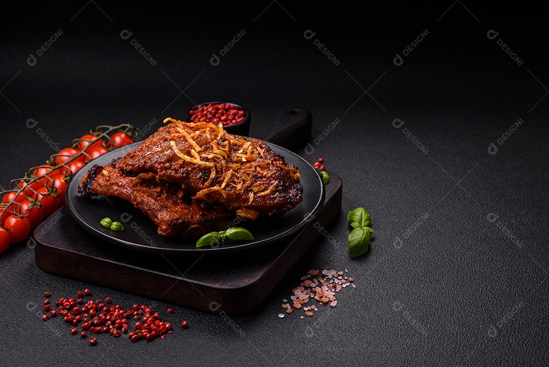 Deliciosas costelas de porco ou de vaca assadas na grelha com sal, especiarias e ervas sobre um fundo escuro de concreto