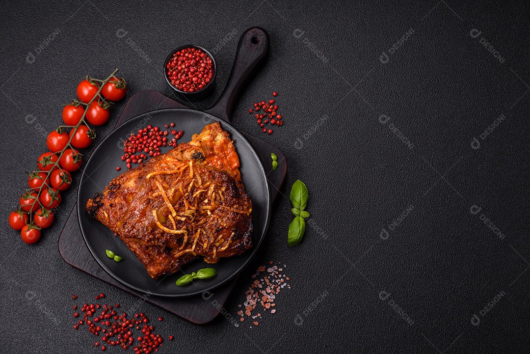 Deliciosas costelas de porco ou de vaca assadas na grelha com sal, especiarias e ervas sobre um fundo escuro de concreto