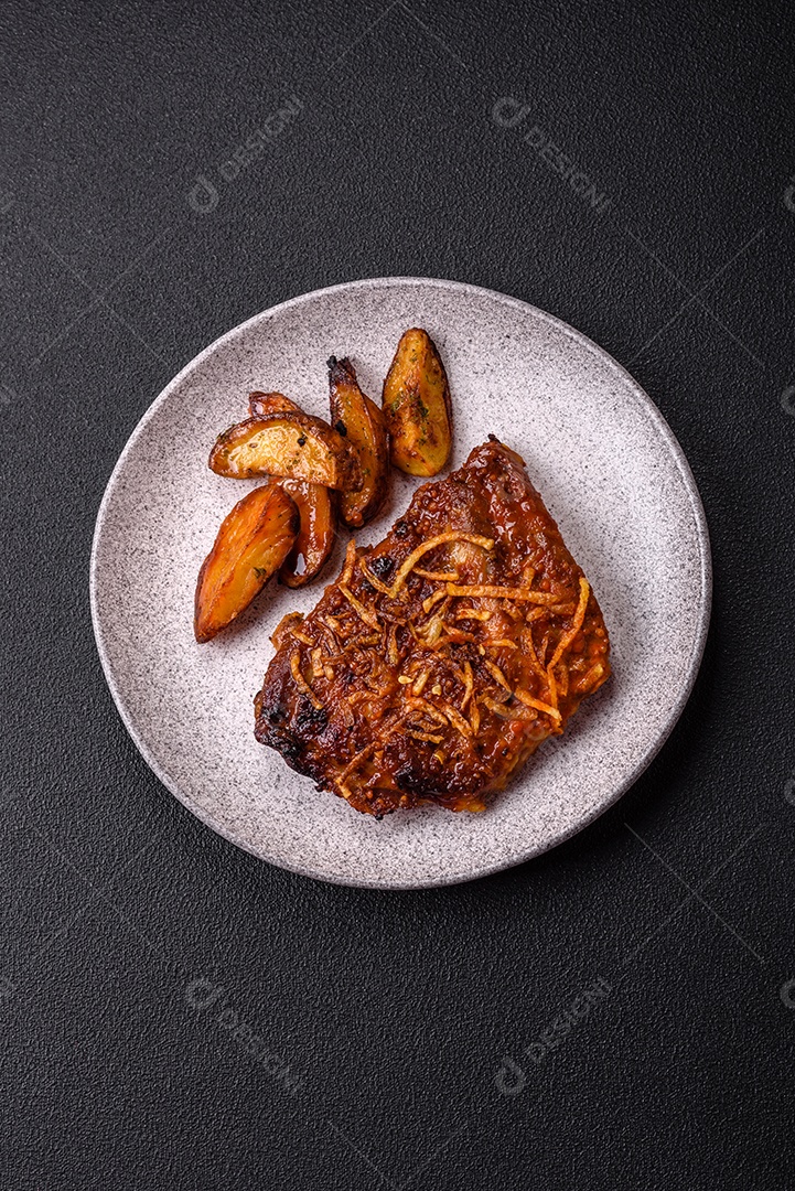 Deliciosas costelas de porco ou de vaca assadas na grelha com sal, especiarias e ervas sobre um fundo escuro de concreto