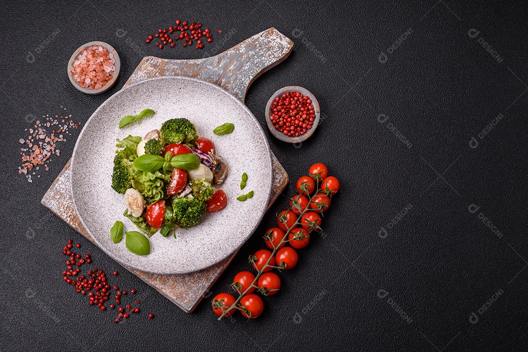 Deliciosa salada fresca e suculenta com ovos de codorna, tomate cereja, folhas de alface com sal, especiarias e ervas sobre um fundo escuro de concreto