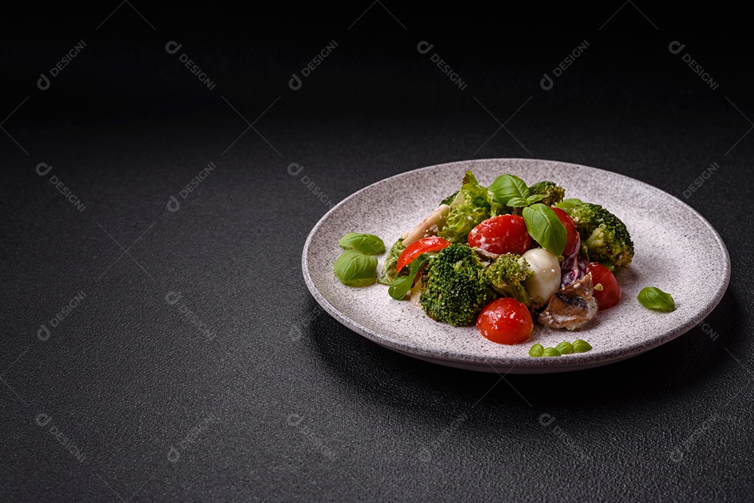 Deliciosa salada fresca e suculenta com ovos de codorna, tomate cereja, folhas de alface com sal, especiarias e ervas sobre um fundo escuro de concreto