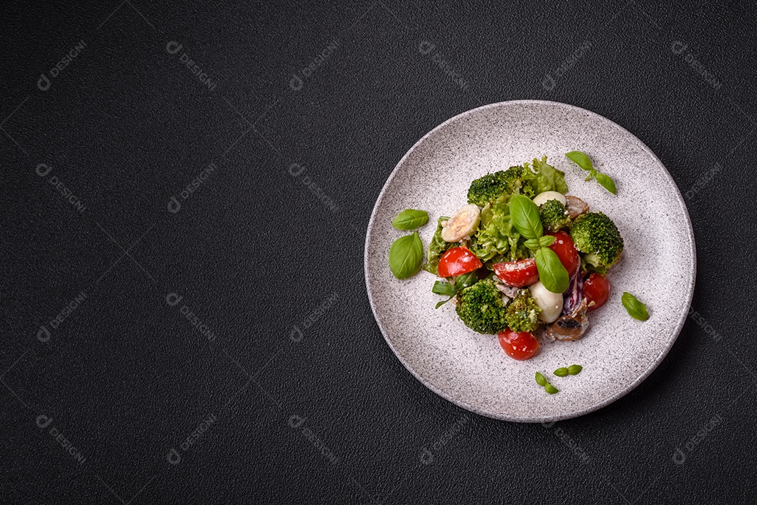 Deliciosa salada fresca e suculenta com ovos de codorna, tomate cereja, folhas de alface com sal, especiarias e ervas sobre um fundo escuro de concreto