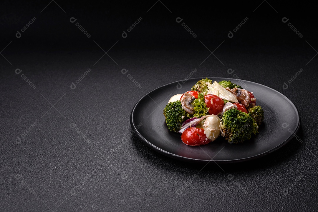 Deliciosa salada fresca e suculenta com ovos de codorna, tomate cereja, folhas de alface com sal, especiarias e ervas sobre um fundo escuro de concreto