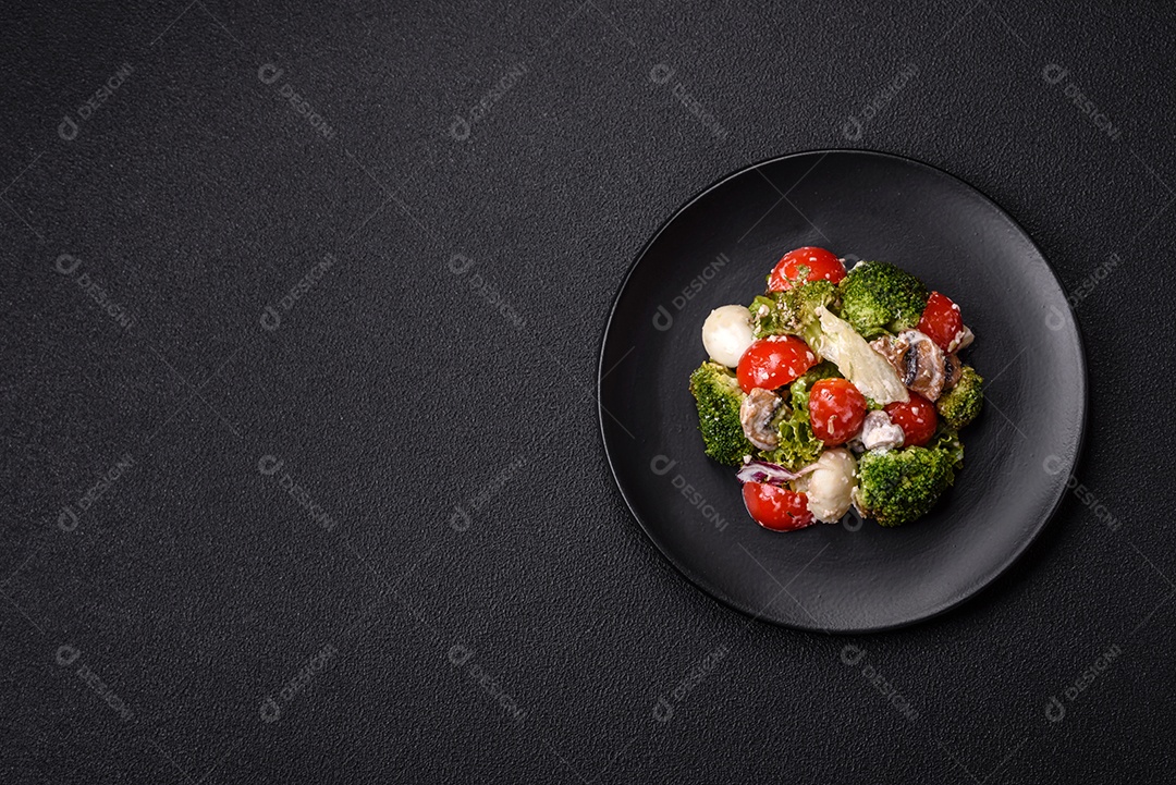 Deliciosa salada fresca e suculenta com ovos de codorna, tomate cereja, folhas de alface com sal, especiarias e ervas sobre um fundo escuro de concreto