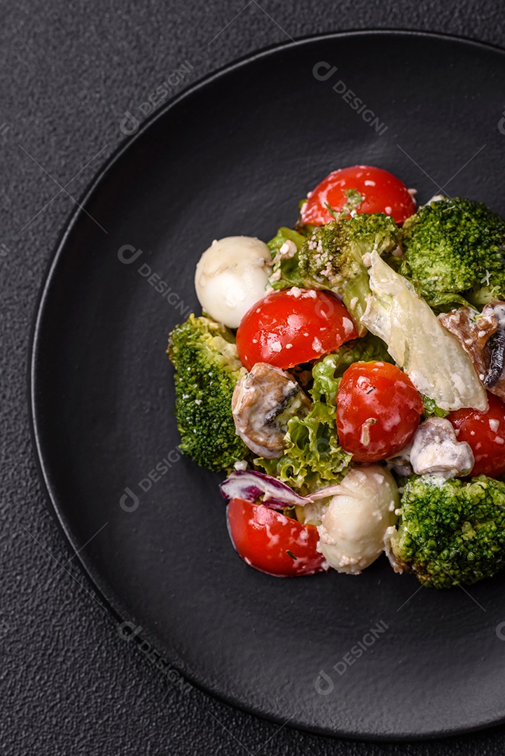 Deliciosa salada fresca e suculenta com ovos de codorna, tomate cereja, folhas de alface com sal, especiarias e ervas sobre um fundo escuro de concreto