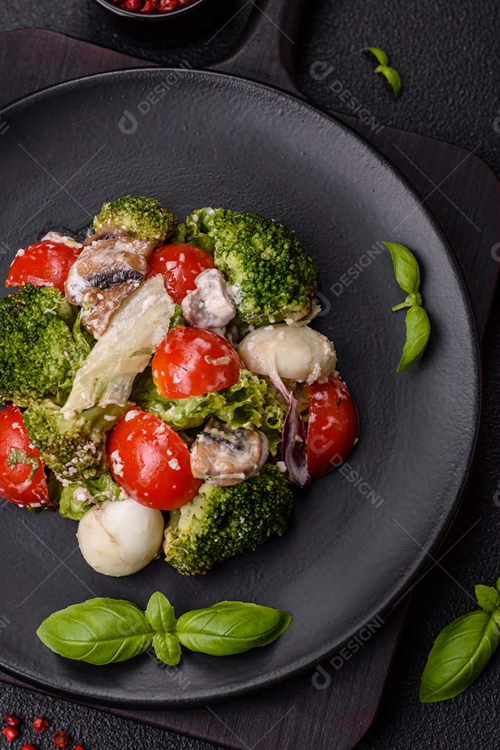 Deliciosa salada fresca e suculenta com ovos de codorna, tomate cereja, folhas de alface com sal, especiarias e ervas sobre um fundo escuro de concreto