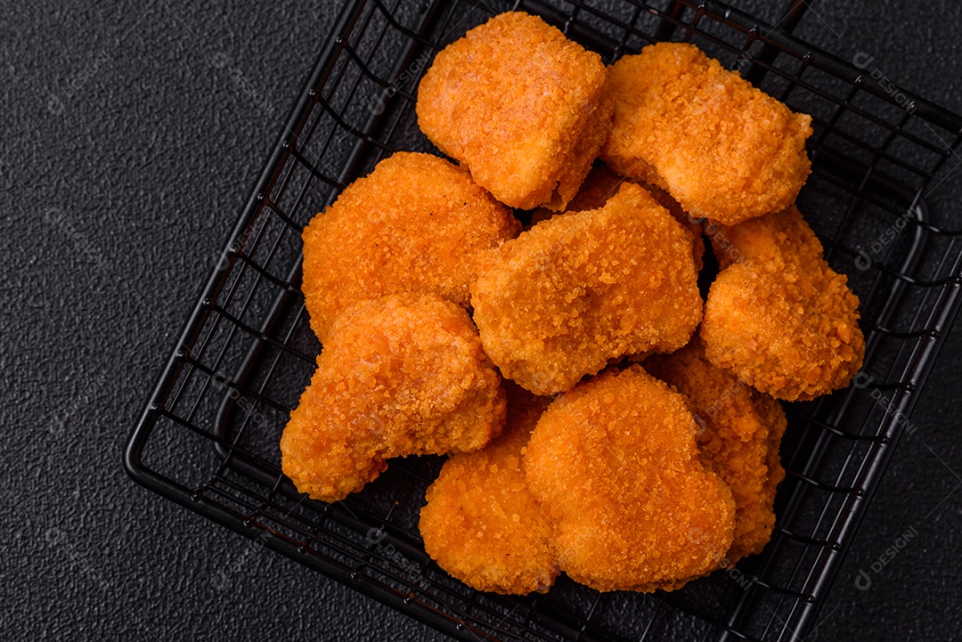 Deliciosos nuggets de frango crocantes frescos em um fundo escuro de concreto. Alimentos não saudáveis, fast food