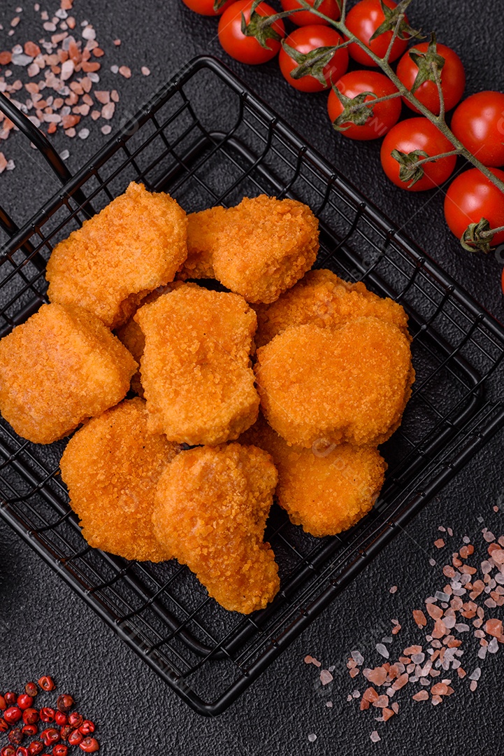 Deliciosos nuggets de frango crocantes frescos em um fundo escuro de concreto. Alimentos não saudáveis, fast food