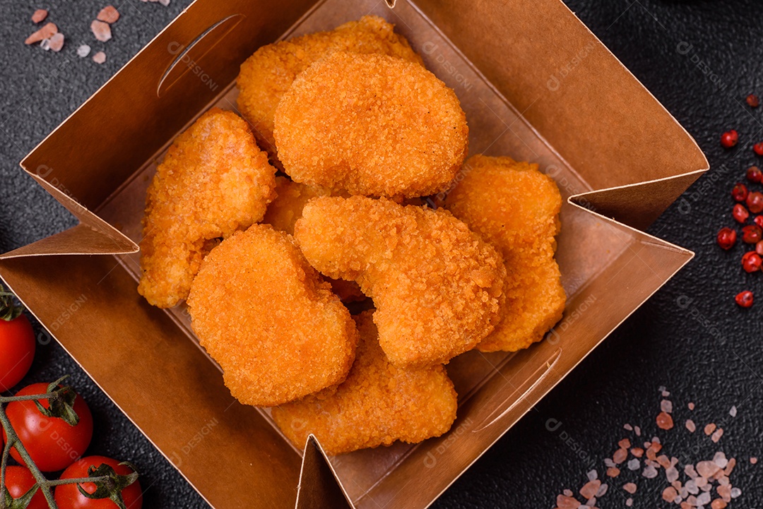Deliciosos nuggets de frango crocantes frescos em um fundo escuro de concreto. Alimentos não saudáveis, fast food