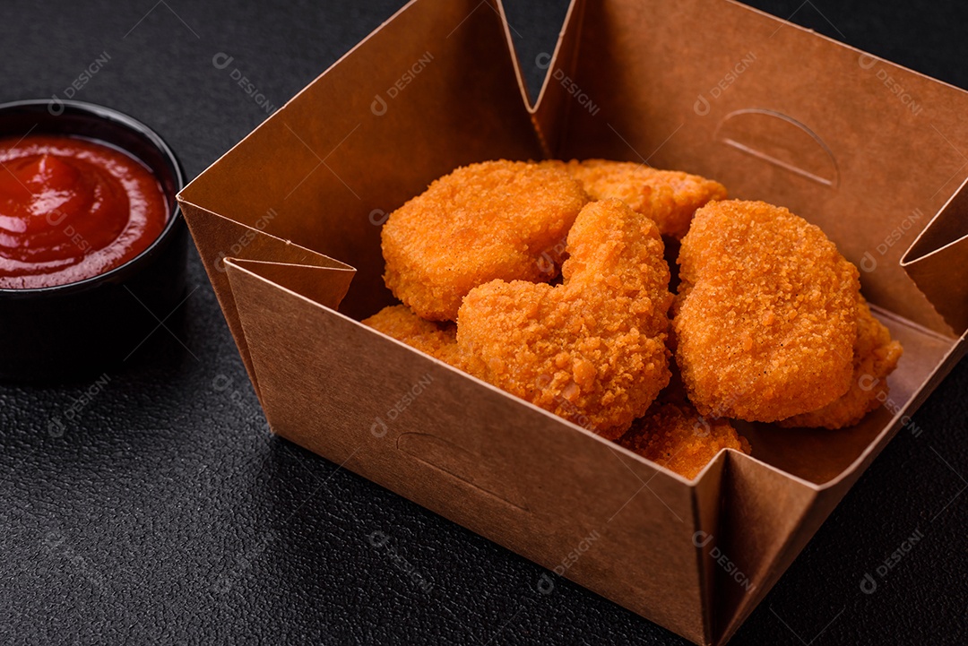 Deliciosos nuggets de frango crocantes frescos em um fundo escuro de concreto. Alimentos não saudáveis, fast food