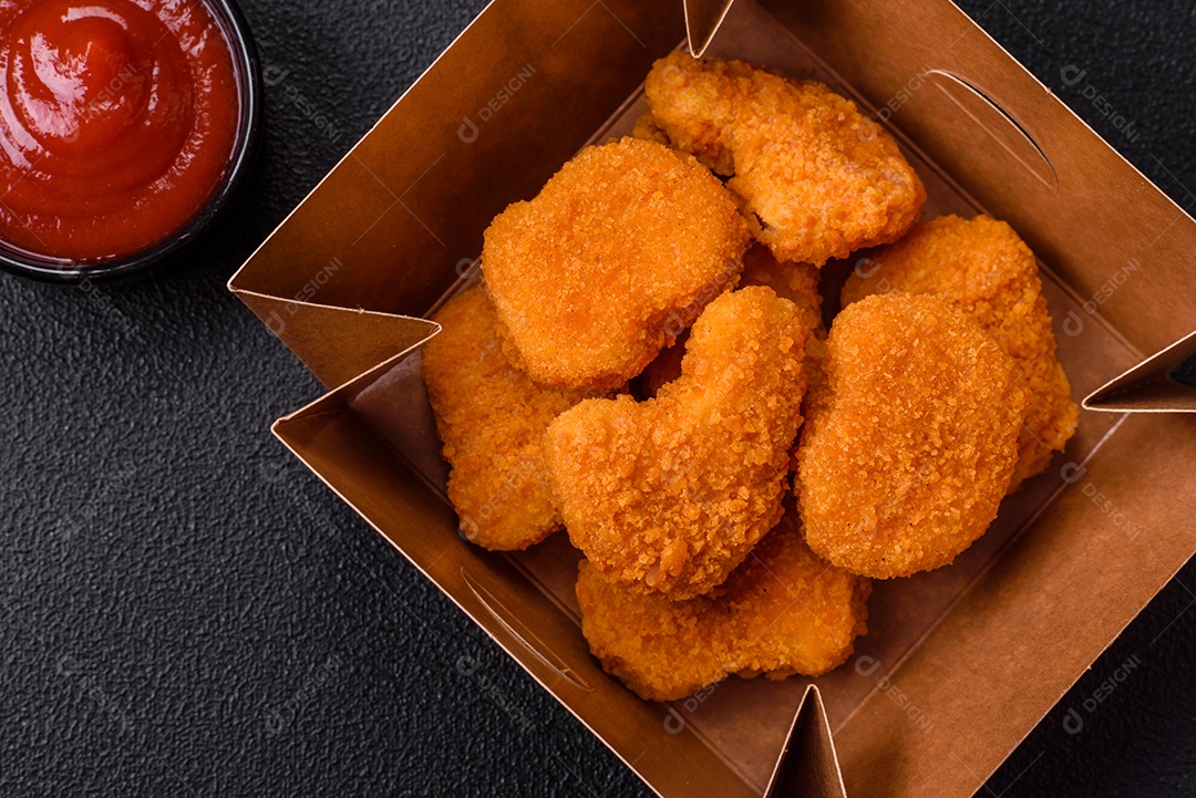 Deliciosos nuggets de frango crocantes frescos em um fundo escuro de concreto. Alimentos não saudáveis, fast food