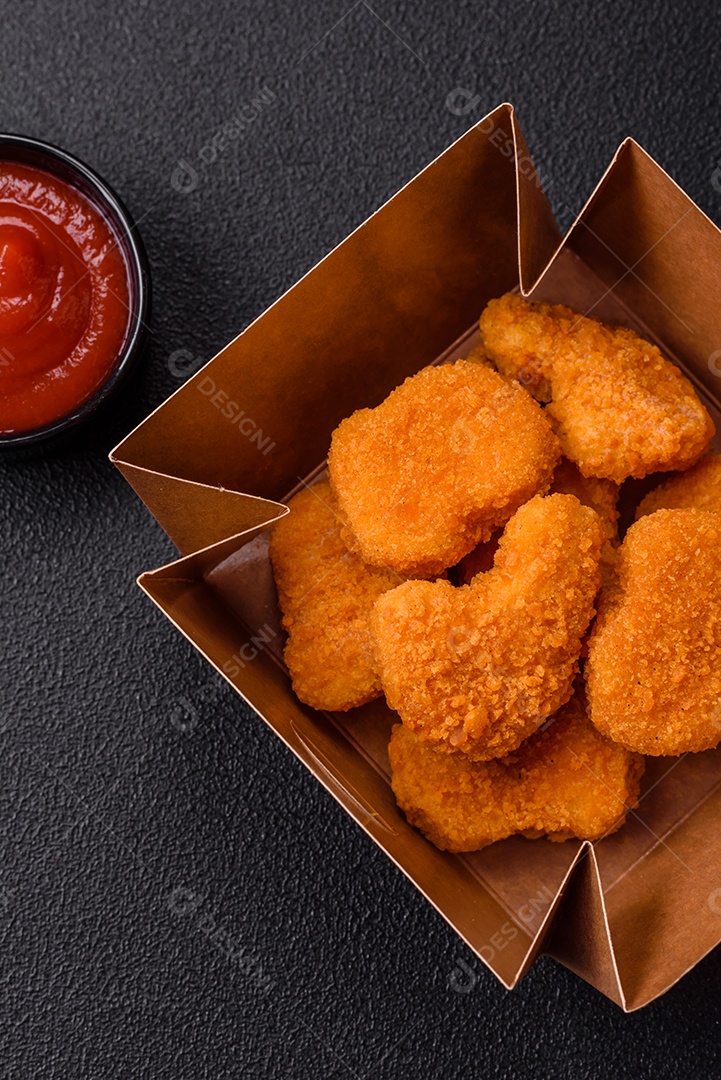 Deliciosos nuggets de frango crocantes frescos em um fundo escuro de concreto. Alimentos não saudáveis, fast food
