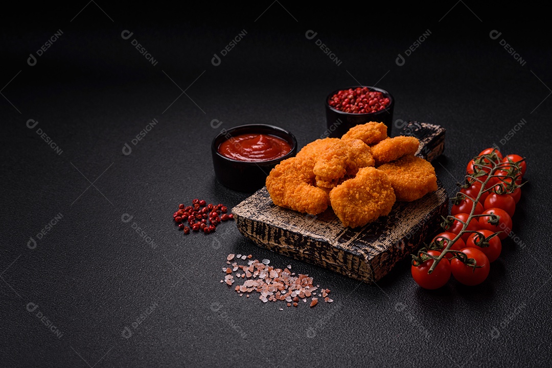 Deliciosos nuggets de frango crocantes frescos em um fundo escuro de concreto. Alimentos não saudáveis, fast food