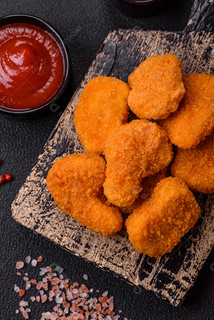 Deliciosos nuggets de frango crocantes frescos em um fundo escuro de concreto. Alimentos não saudáveis, fast food